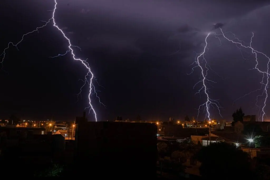 Intense lightning illuminates a city during a nighttime thunderstorm, showcasing nature's power.