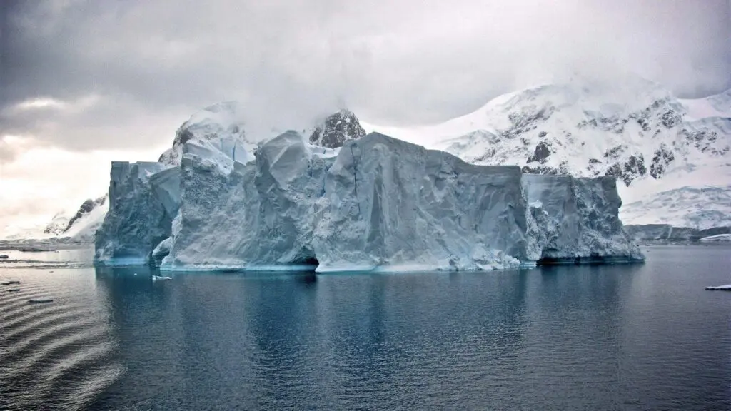 white iceberg near white mountains