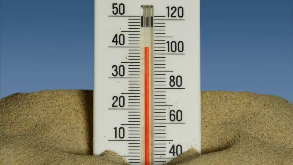 A thermometer in the sand with a blue sky in the background