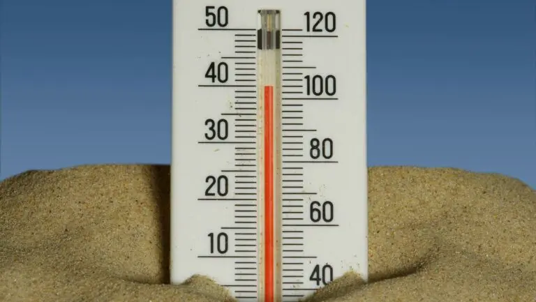 A thermometer in the sand with a blue sky in the background