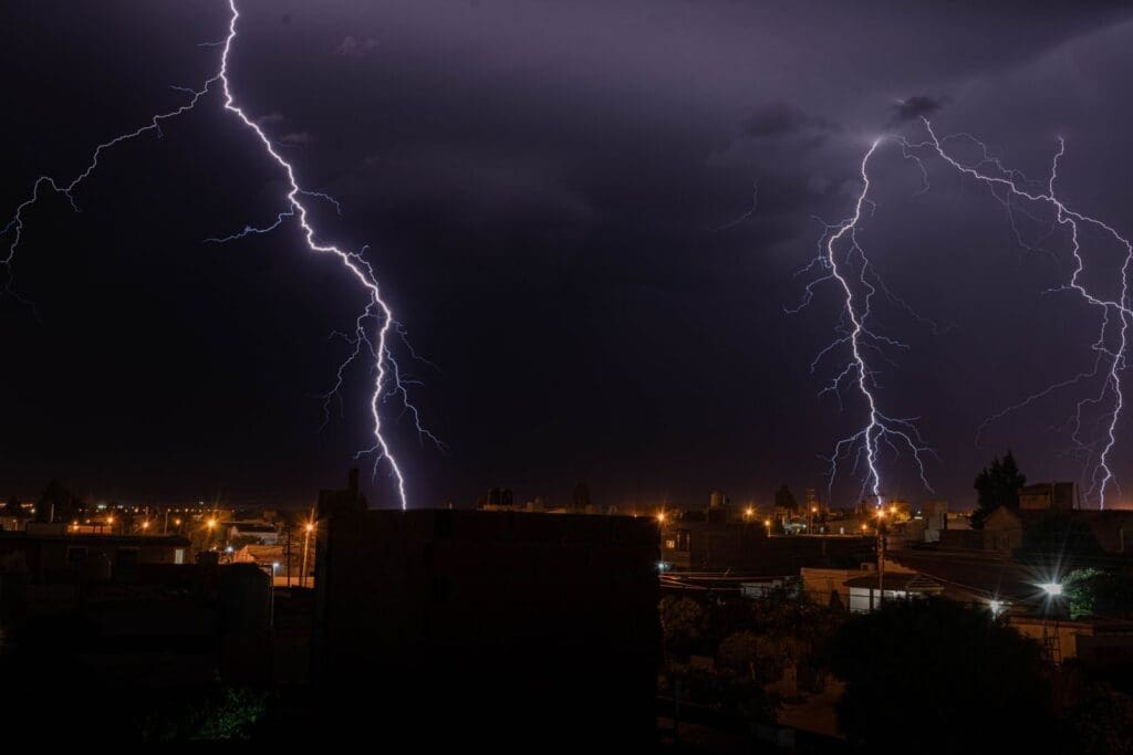 Intense lightning illuminates a city during a nighttime thunderstorm, showcasing nature's power.