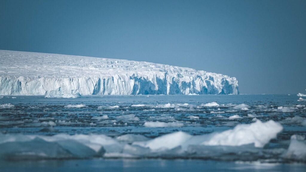 A vast icy landscape with towering icebergs and a serene, calm sea in Antarctica.