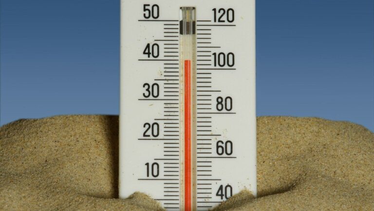 A thermometer in the sand with a blue sky in the background